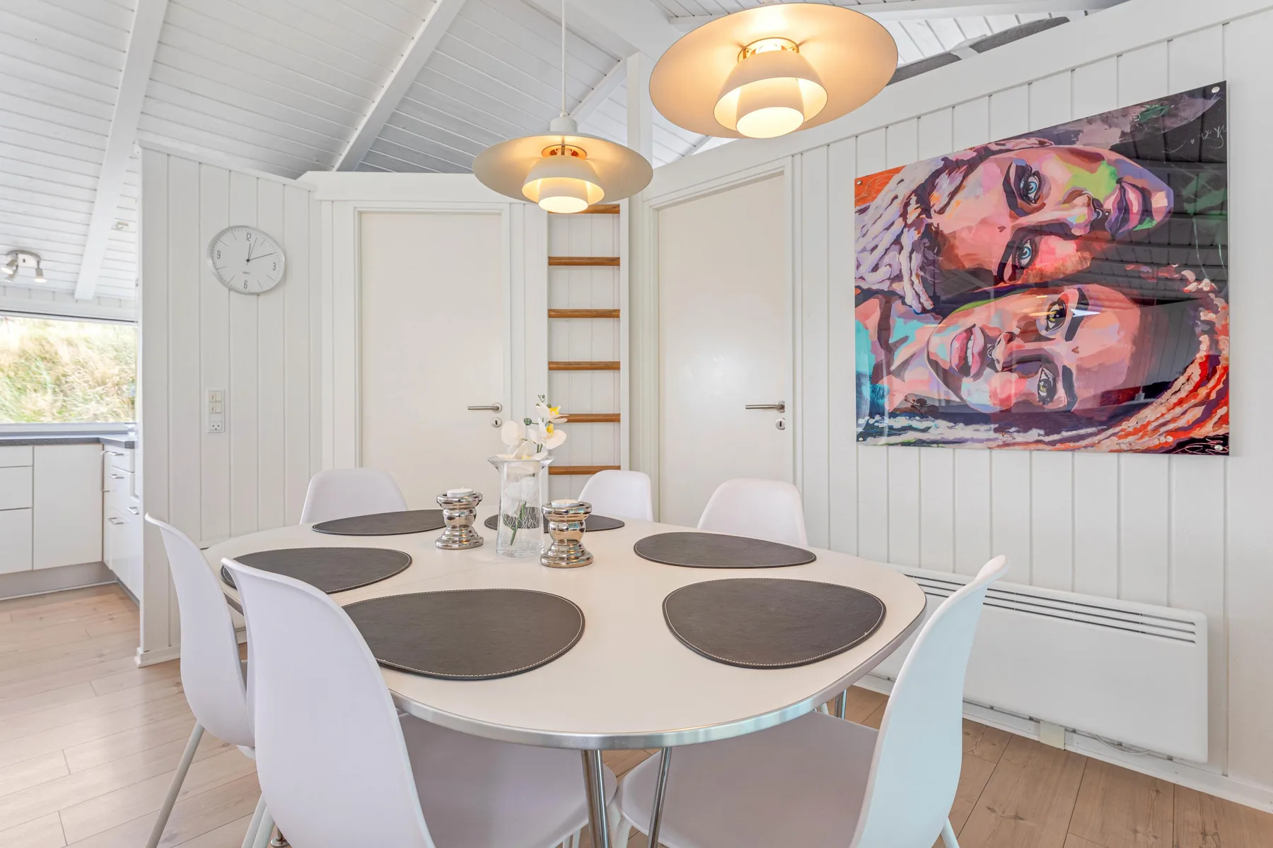 Un comedor luminoso con la mesa puesta y una obra colorida en la pared.