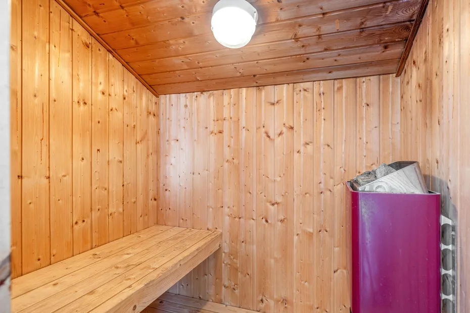 Una sauna revestida de madera con un banco largo y un calentador.
