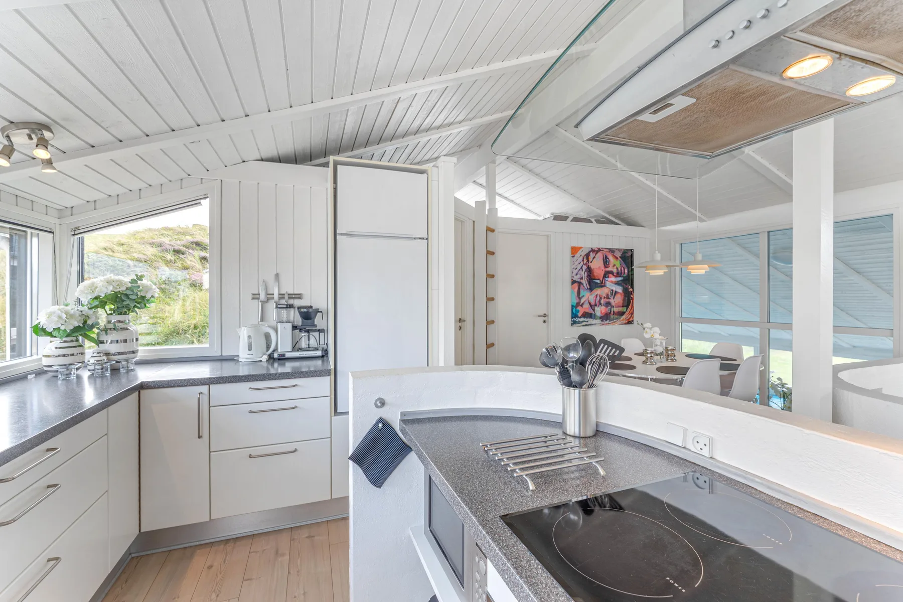 Una cocina luminosa con una encimera central y grandes ventanas.