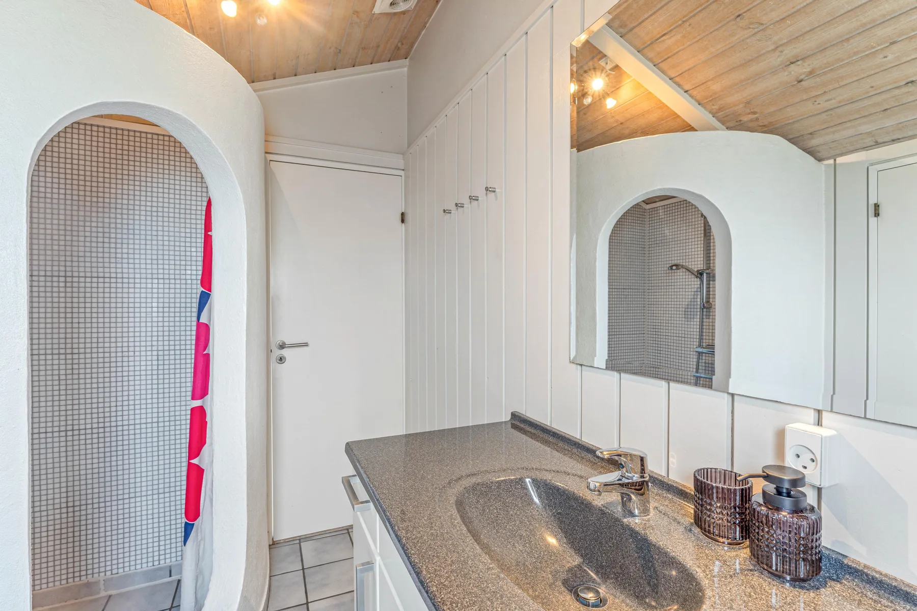 Un lavabo de baño con fregadero y un rincón de ducha alicatado.