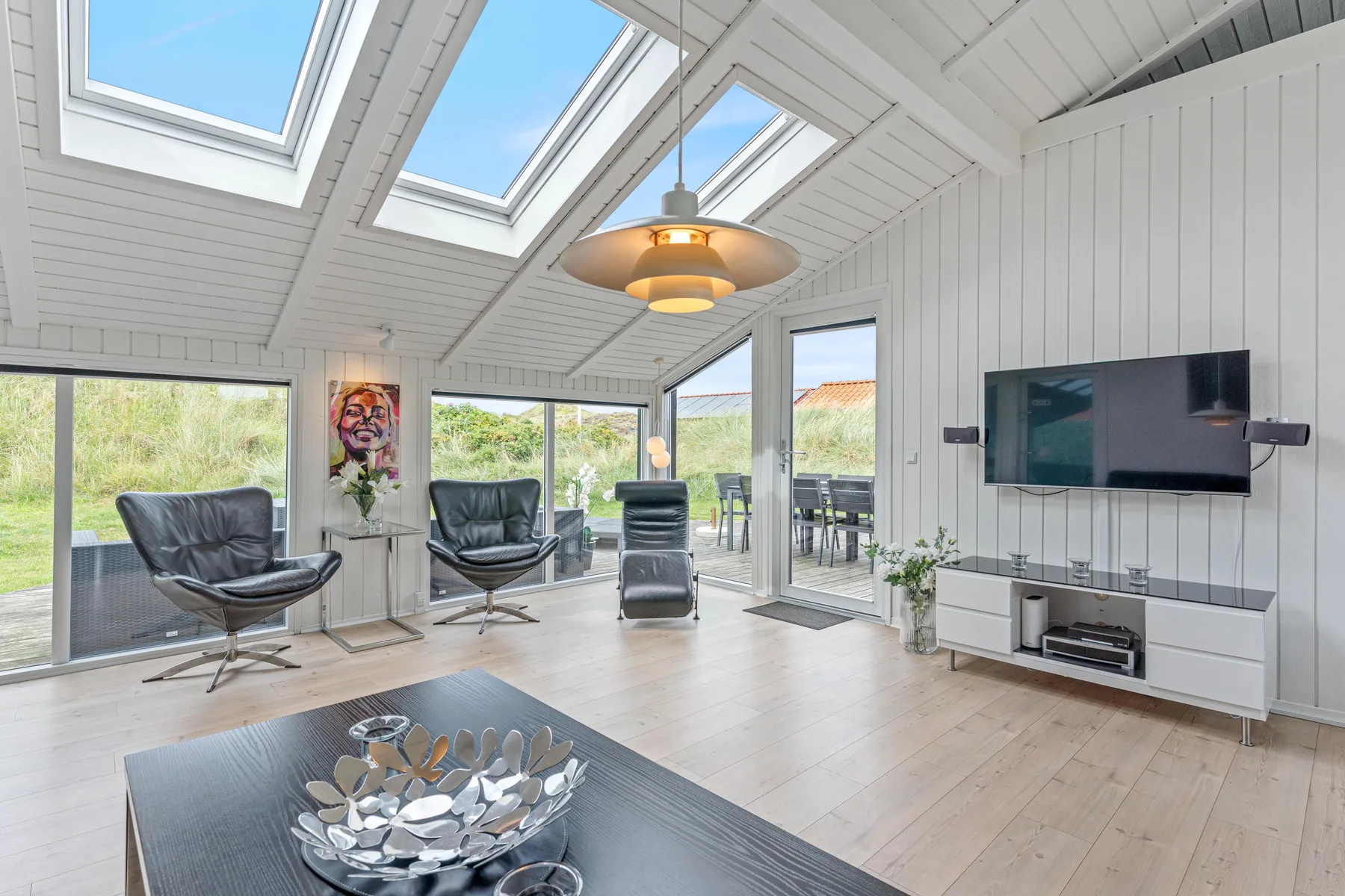 Una sala luminosa con tragaluces y puertas de vidrio que dan a un patio.