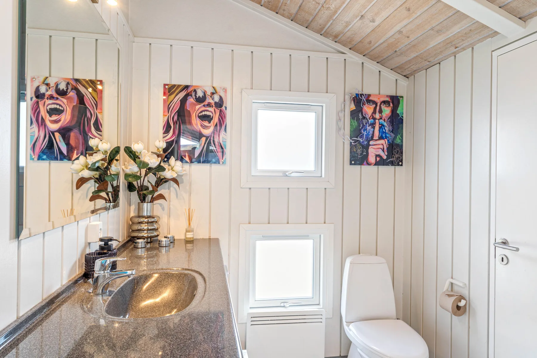 Un baño compacto con lavabo, inodoro y arte colorido en las paredes.