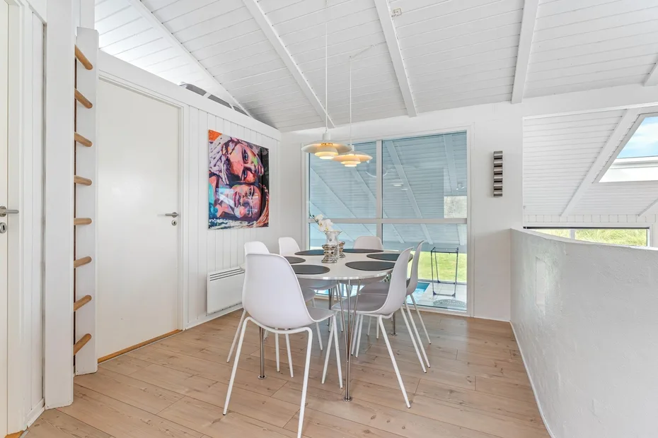 Un comedor luminoso con una mesa y sillas junto a grandes ventanas.