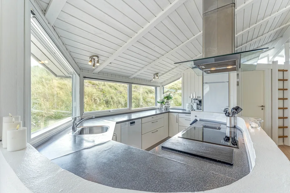 Una cocina moderna y luminosa con una encimera curva y ventanales.