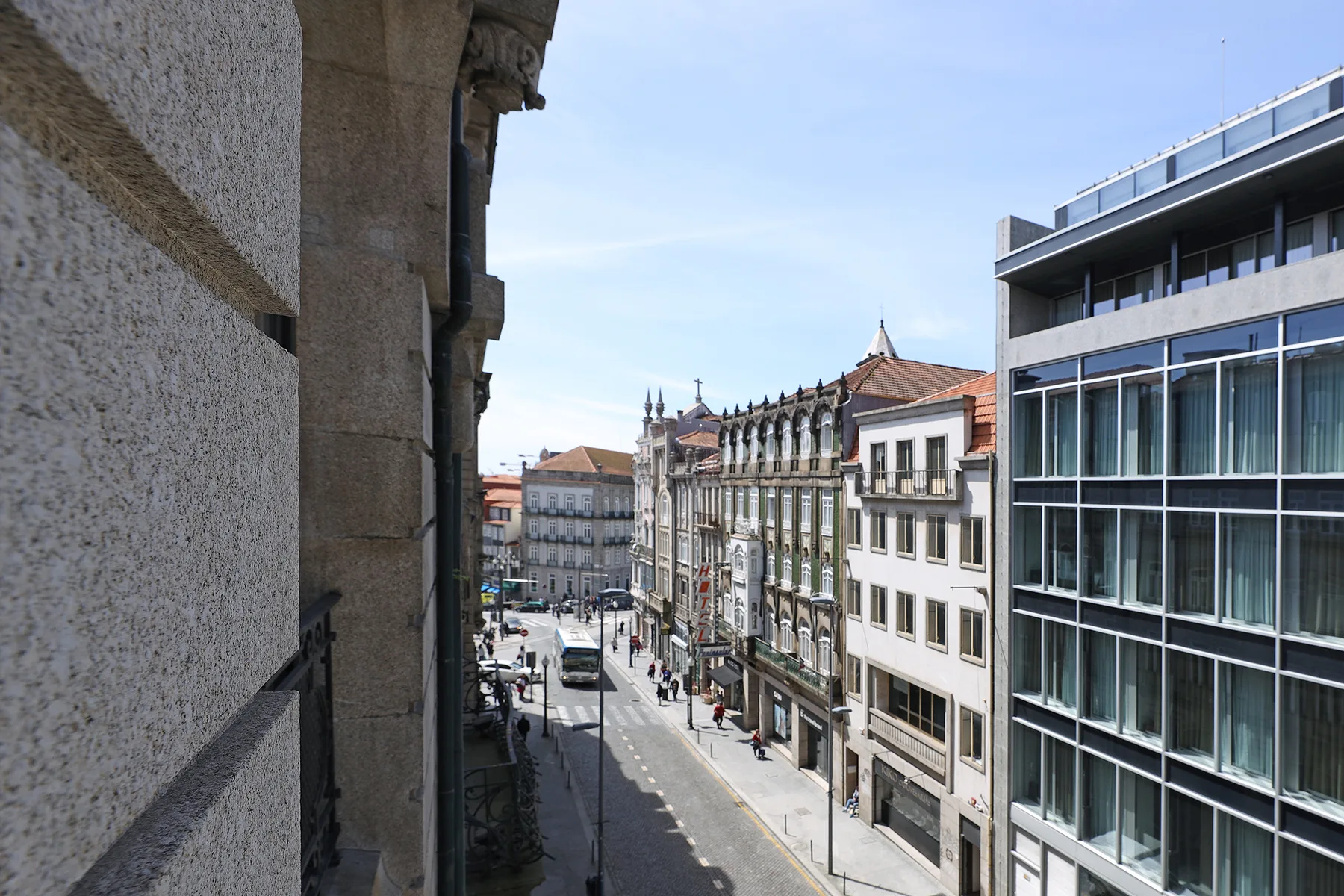 Vista de una calle de Oporto, con un edificio moderno acristalado junto a fachadas antiguas.