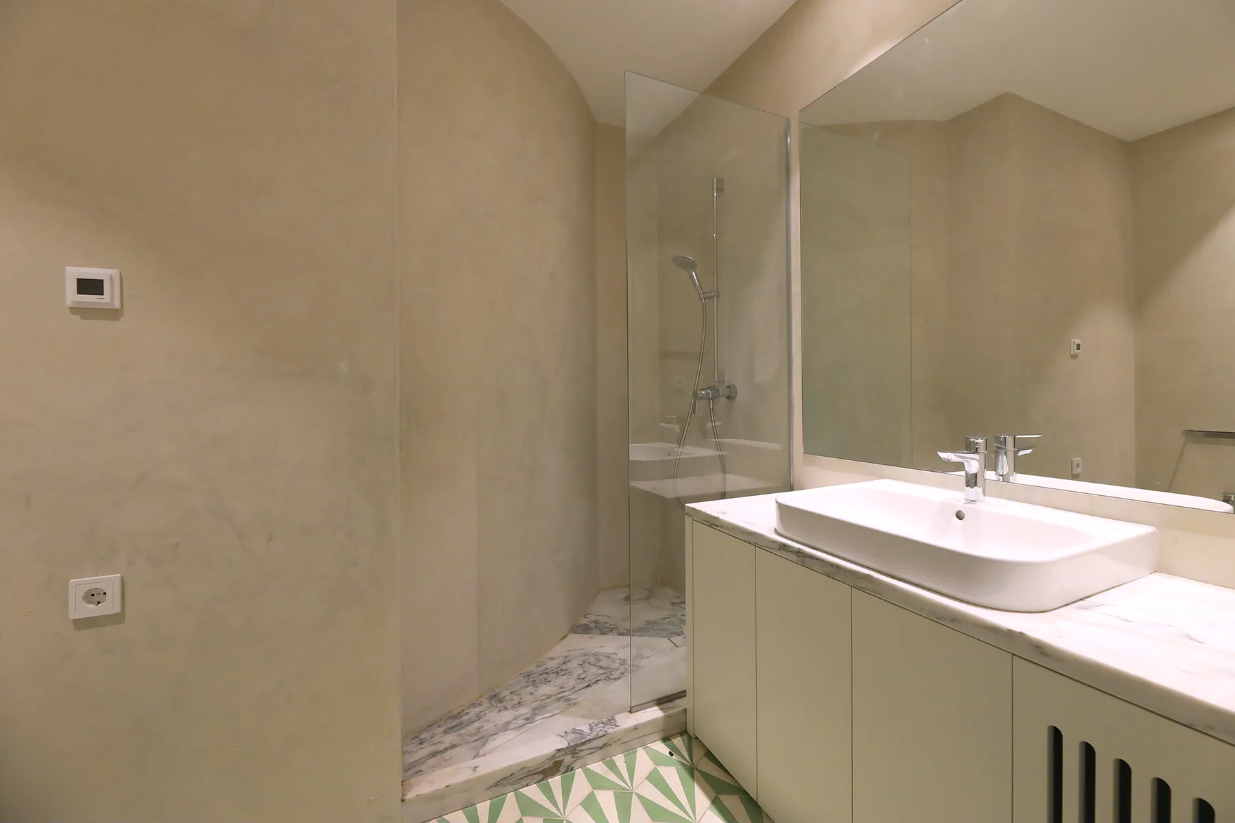 Un baño con lavabo y ducha de vidrio.