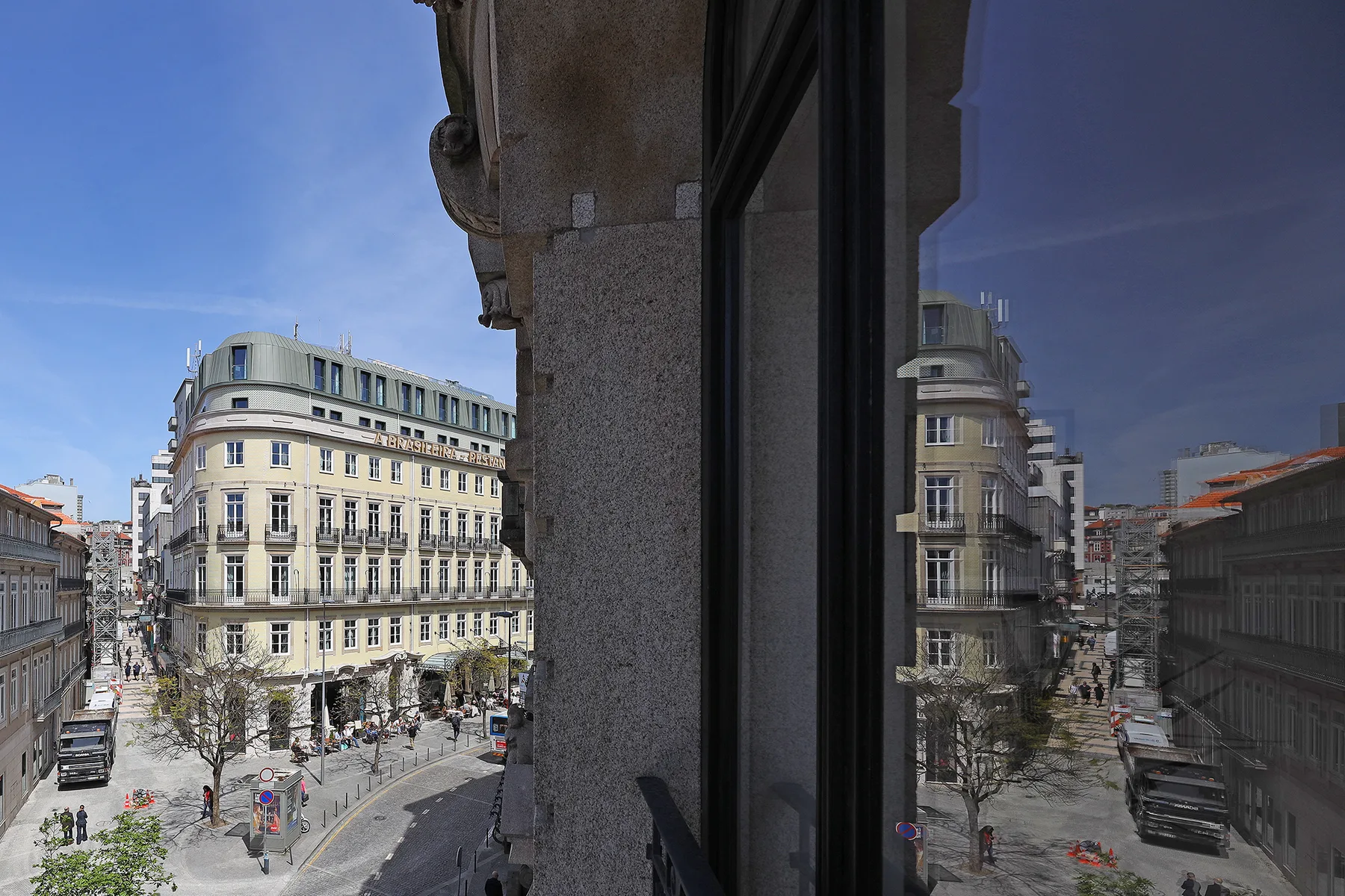 Una calle urbana y los edificios cercanos se ven a través de una ventana.
