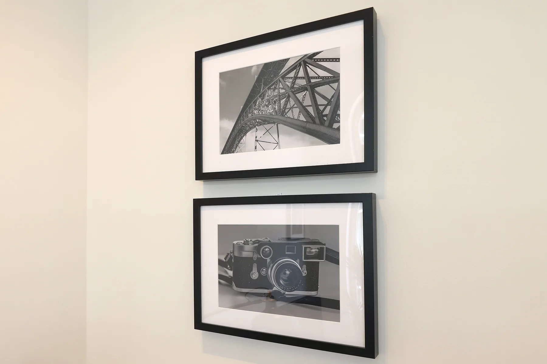 Dos fotografías en blanco y negro enmarcadas cuelgan de una pared clara.