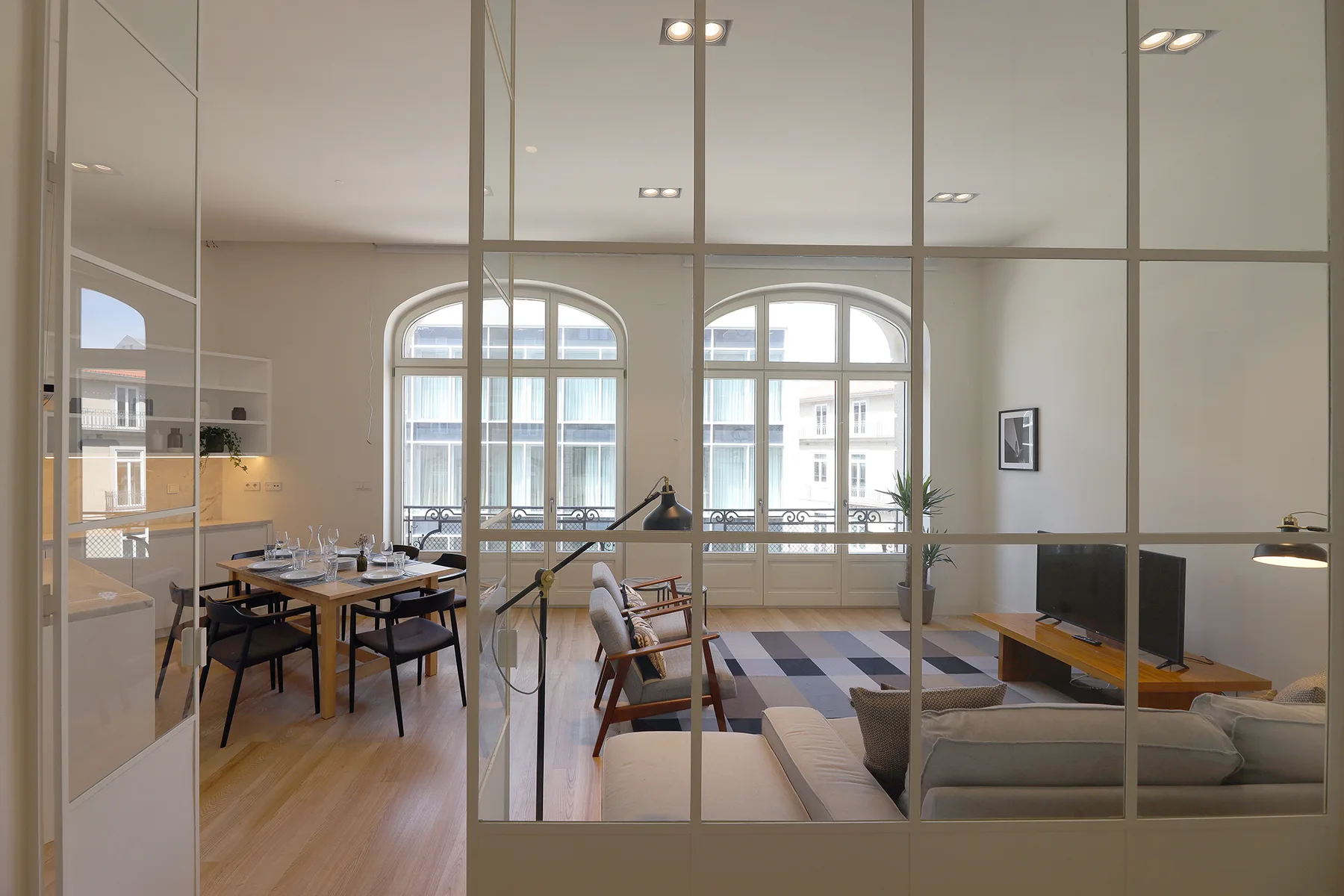 Open-plan living and dining area with seating, a table, and large arched windows.