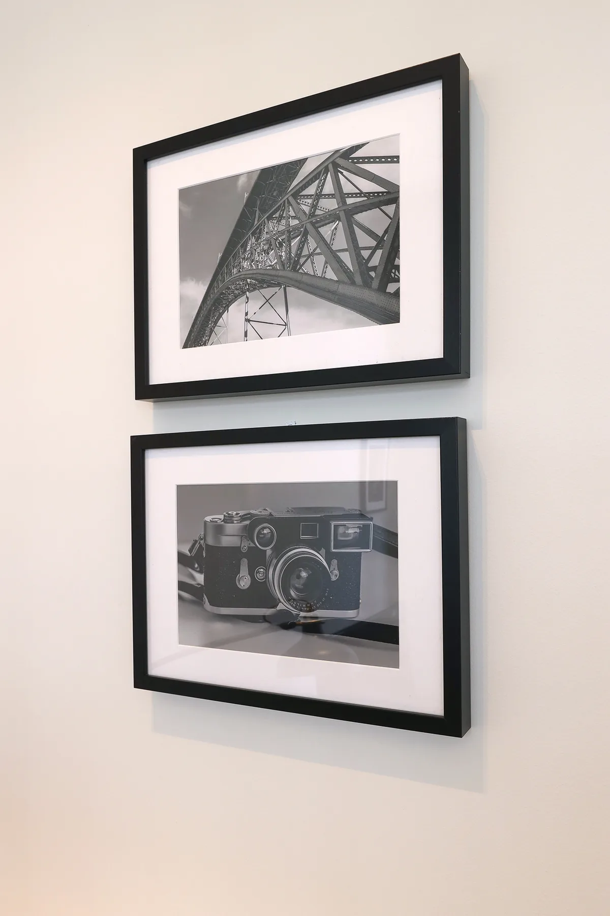 Dos fotografías en blanco y negro cuelgan enmarcadas sobre una pared clara.