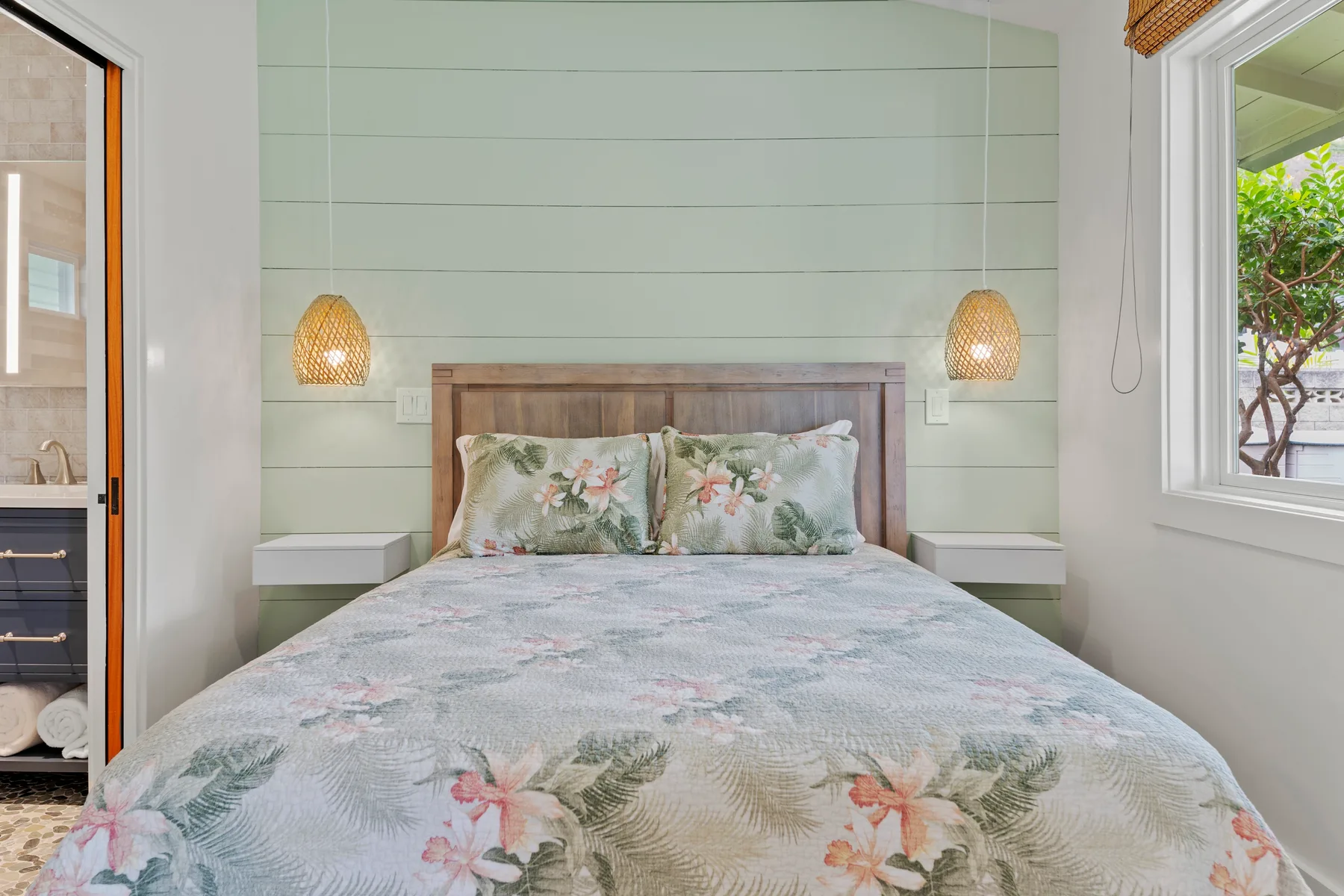 Un dormitorio con una cama cubierta con ropa de cama floral y luces en la pared.