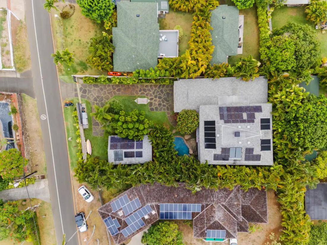 Vista aérea de una propiedad rodeada de vegetación, con paneles solares en varios tejados.