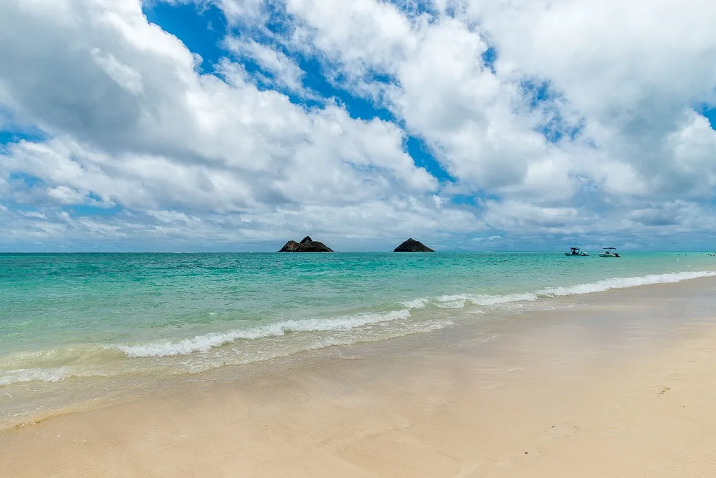 Una playa de arena se encuentra con aguas turquesas bajo un cielo nublado.