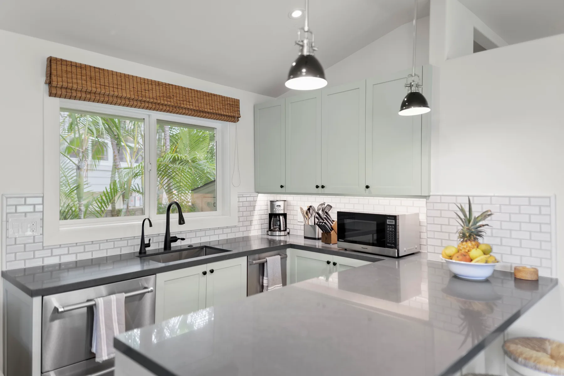 Una cocina luminosa con gabinetes claros, encimeras oscuras y una gran isla central.