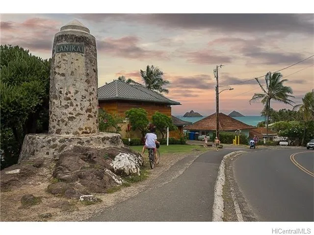 Una escena costera al atardecer, con un monumento de piedra junto a la carretera curva.