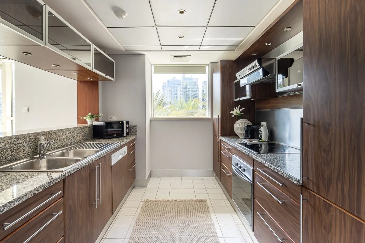 Una cocina estrecha con encimeras y gabinetes a ambos lados, junto a una ventana.
