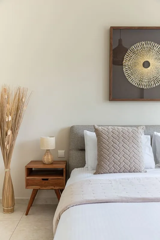 Un dormitorio con una cama tendida y una mesa de noche de madera.