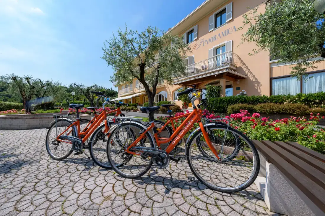 Hotel Panoramica facade with orange bicycles for guests, among olive trees and flowers