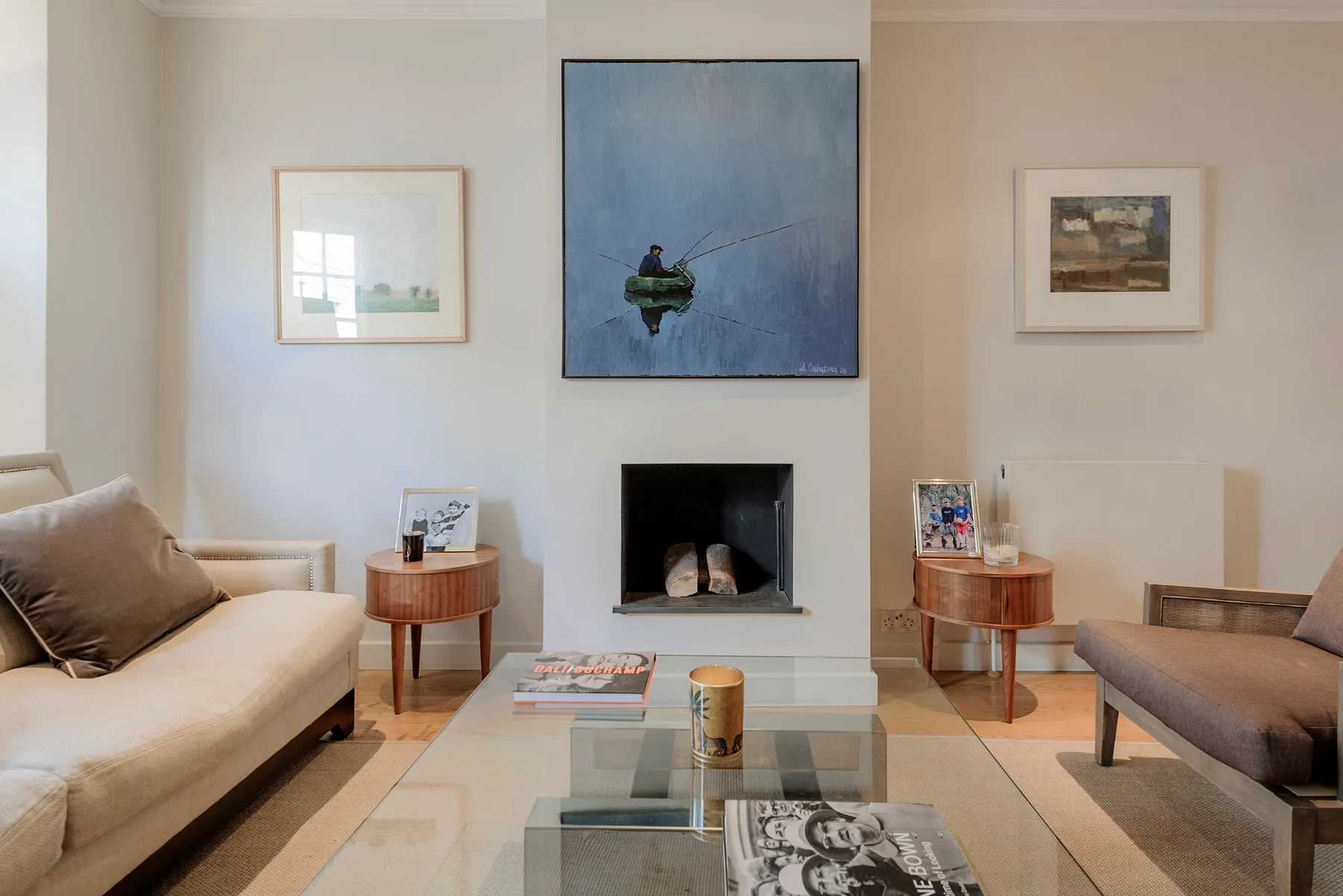 Una sala de estar con asientos, una chimenea y obras enmarcadas.