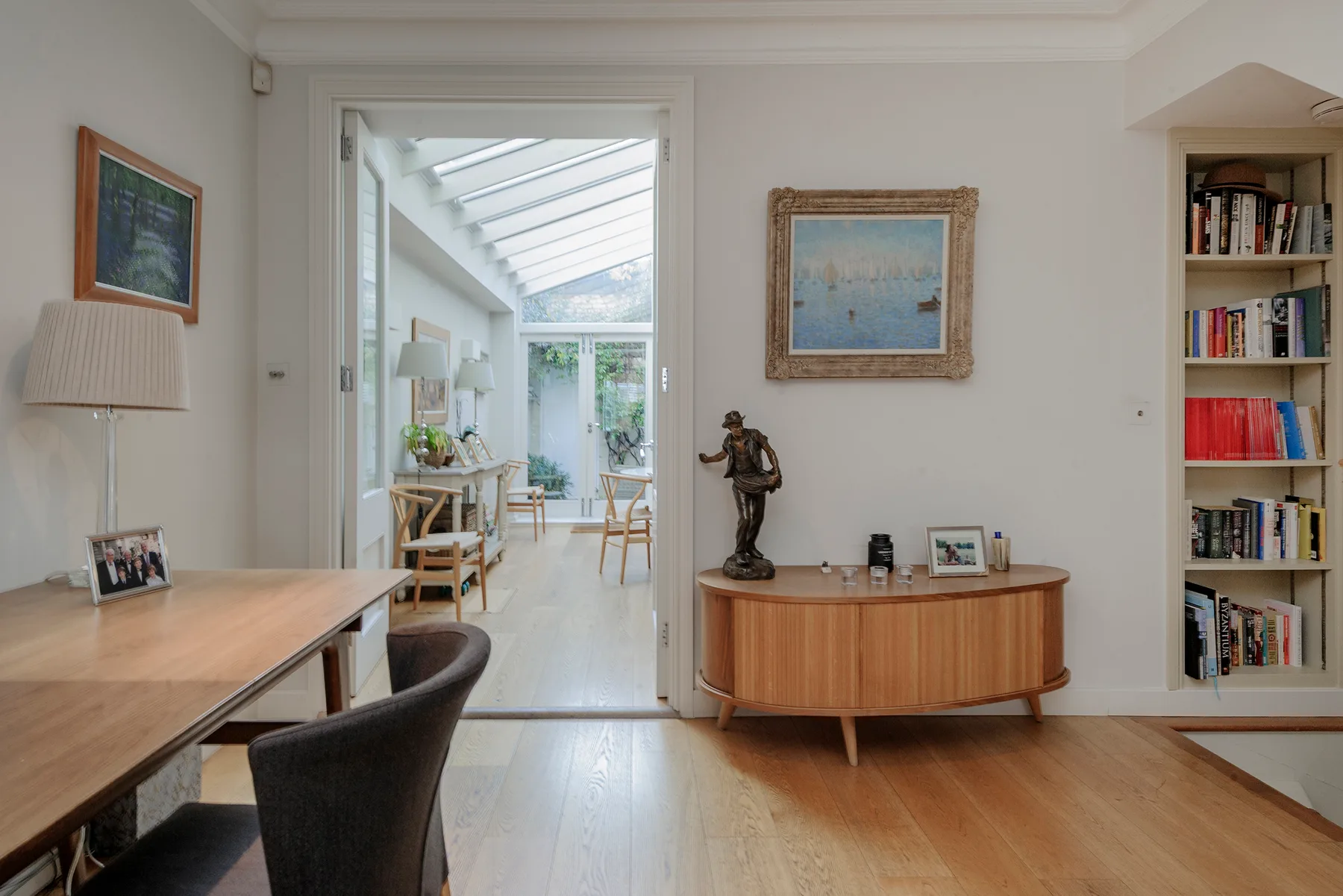 Un estudio luminoso se abre a una galería acristalada con una mesa de comedor.