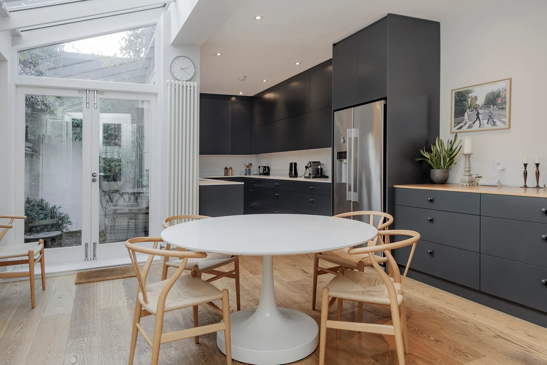 A bright kitchen and dining area with dark cabinets and a round table.