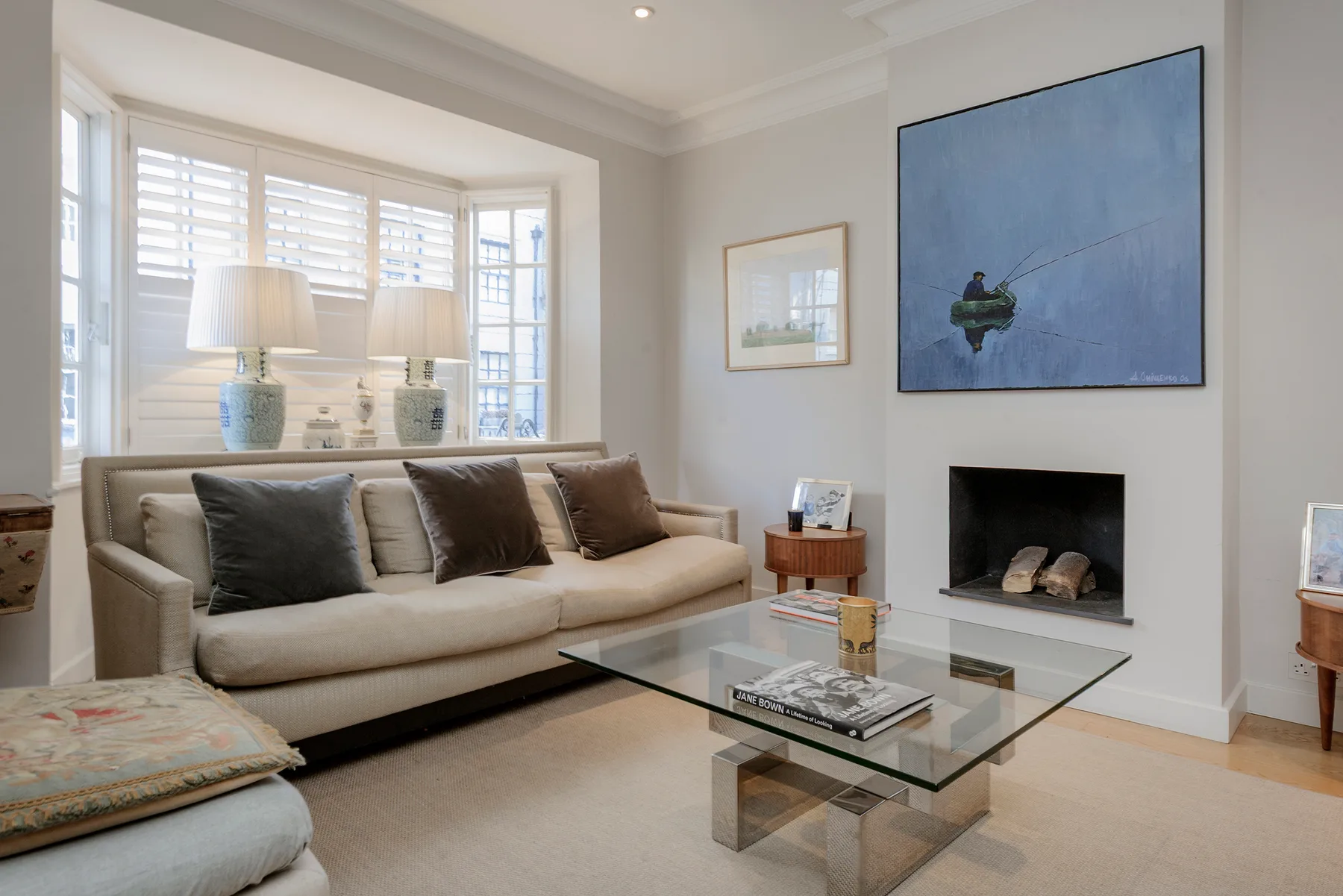 Una sala luminosa con sofá beige, mesa de centro de vidrio y chimenea.