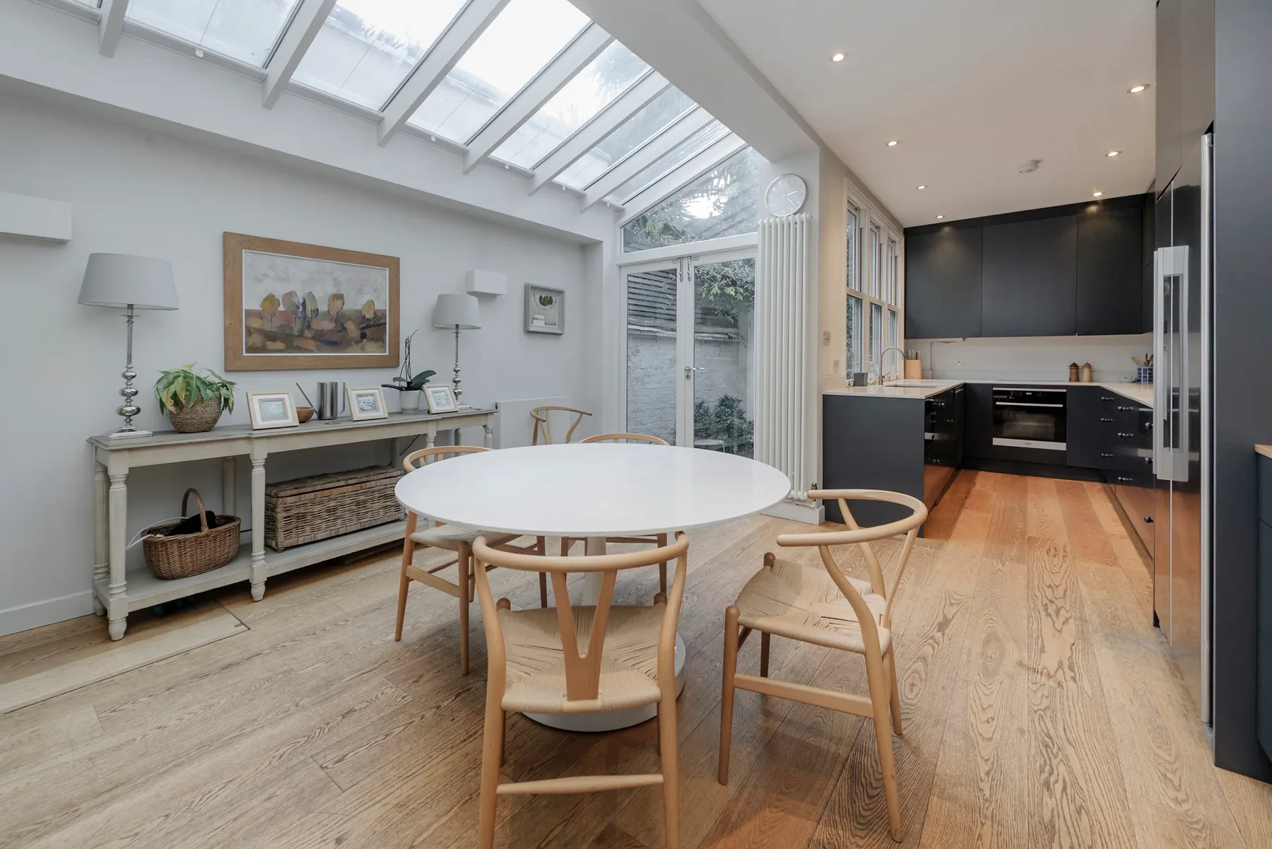 A bright dining area with a round table beside an open kitchen.