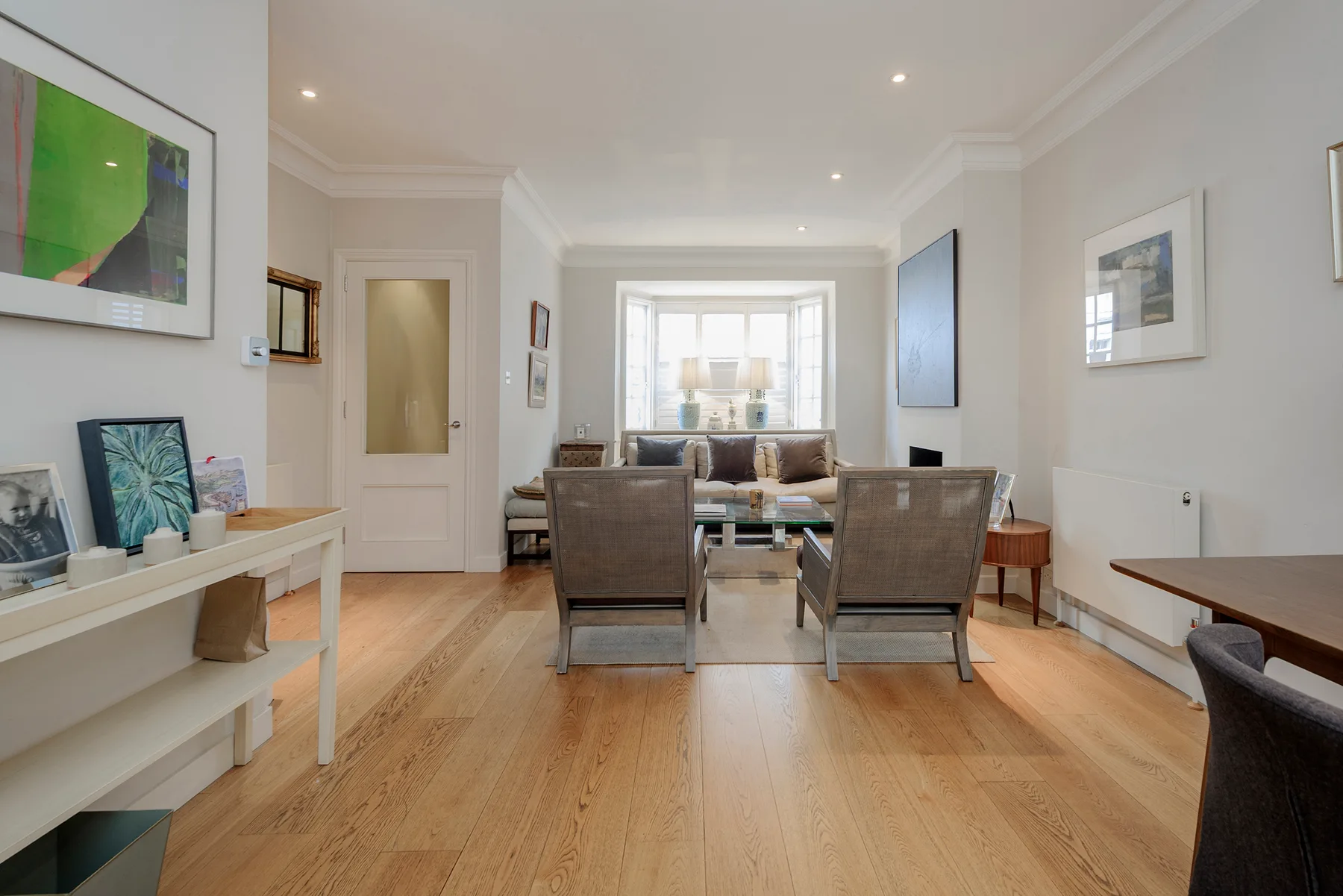 Una sala luminosa con una mesa de comedor, asientos y cuadros enmarcados.