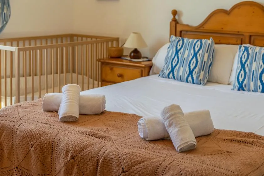 A bedroom with a wooden bed, blue patterned pillows, and a crib.