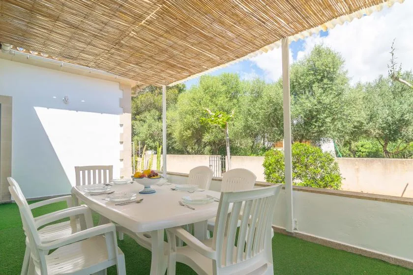 A shaded outdoor dining area with a table and seating beneath a reed canopy.