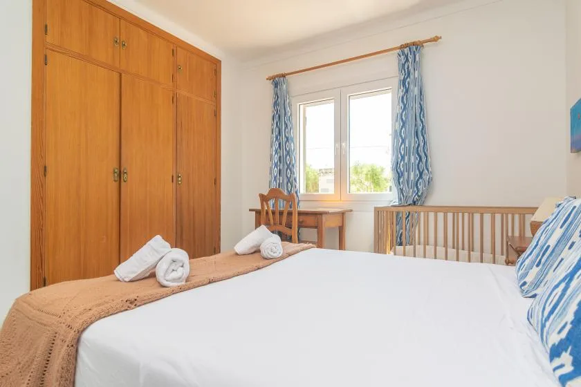 A bedroom with a bed, wooden wardrobe, and a window with blue curtains.