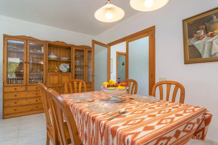 A dining room with a rectangular table covered by an orange patterned cloth.