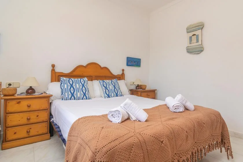 Bedroom with a double bed, patterned pillows, and a wooden dresser.