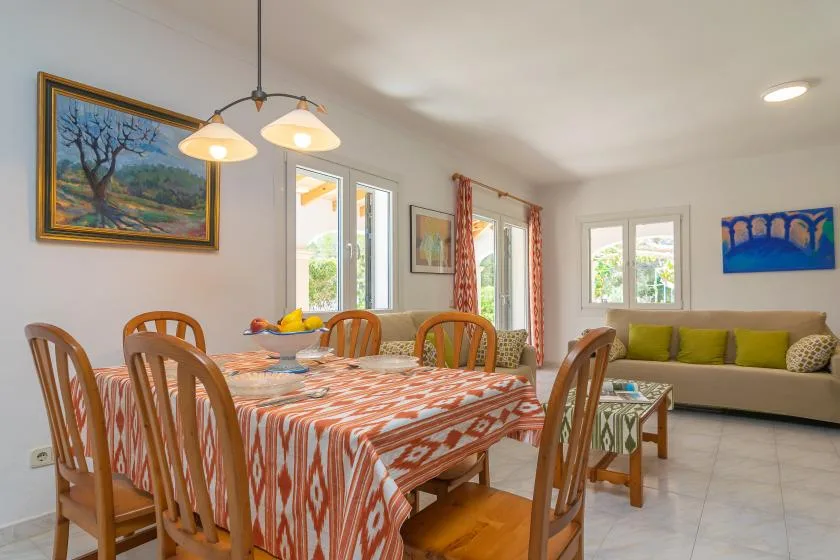 A dining area with a patterned tablecloth beside a living room seating area.