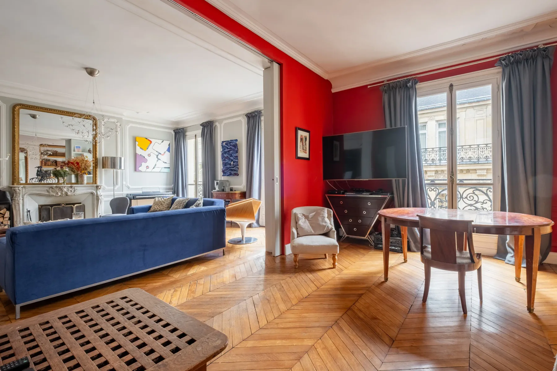 Una sala luminosa con un sofá azul y una mesa de comedor junto a las ventanas.