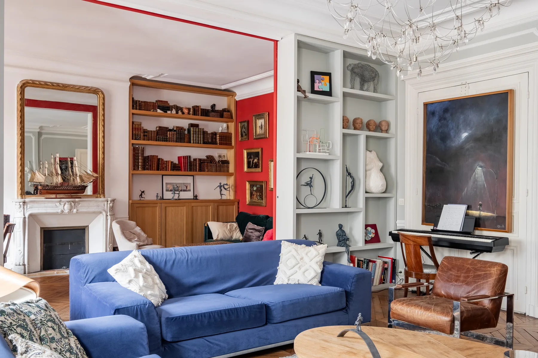 Una sala de estar con asientos azules, estanterías y un piano.