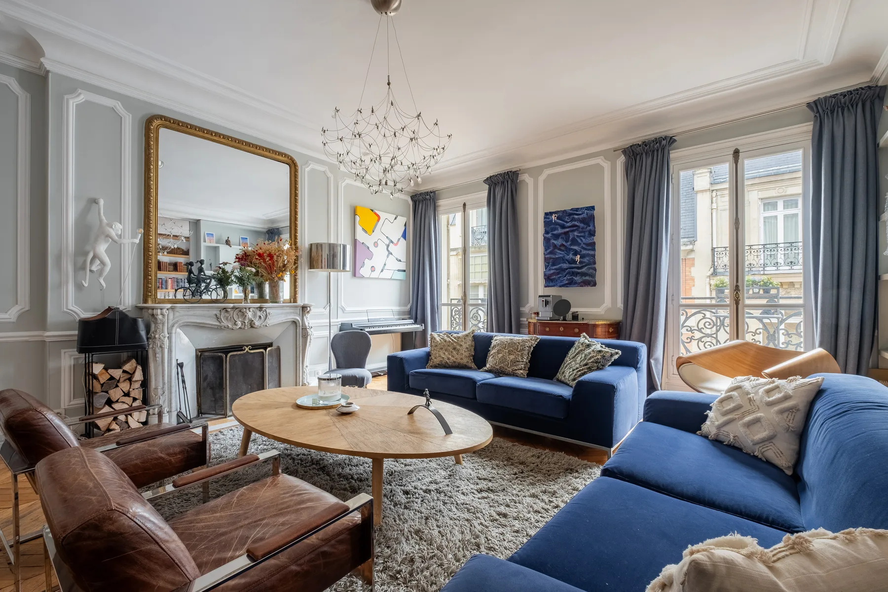 Una sala luminosa con asientos azules, una mesa de centro redonda y ventanas altas.