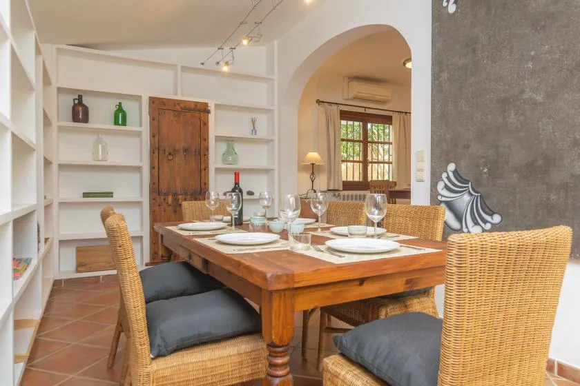 A dining area with a wooden table set with plates and glassware beside built-in shelves.