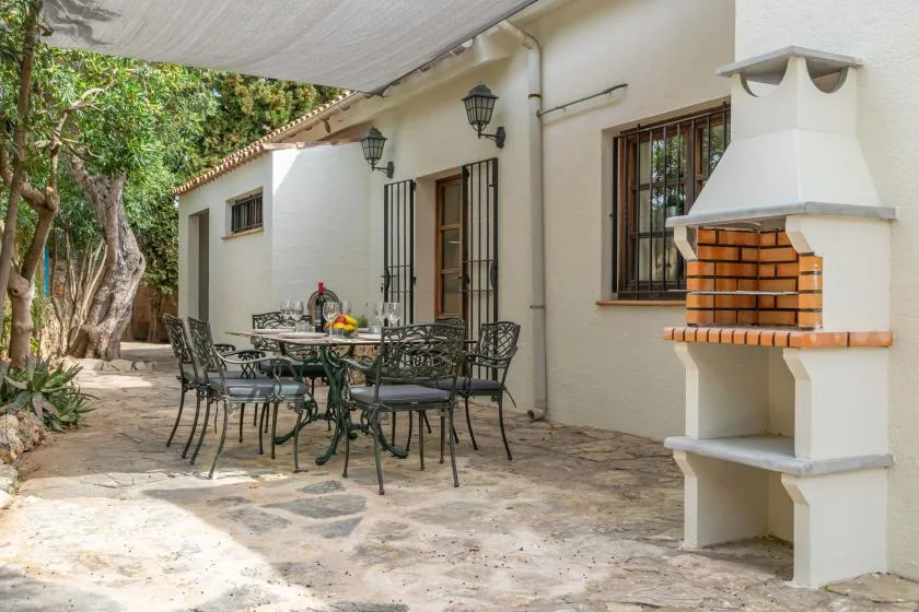 An outdoor dining patio with a table, seating, and a built-in barbecue.