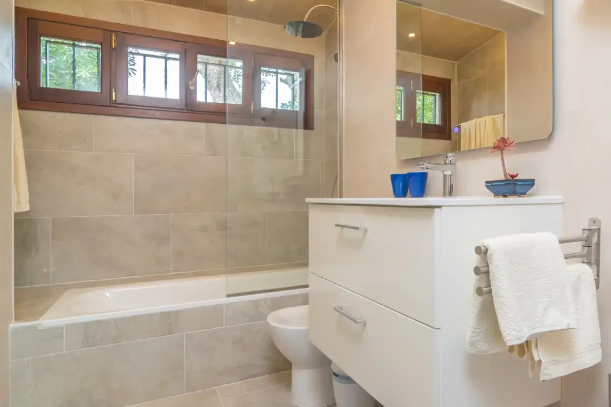 A tiled bathroom with a bathtub, sink, and wall mirror.