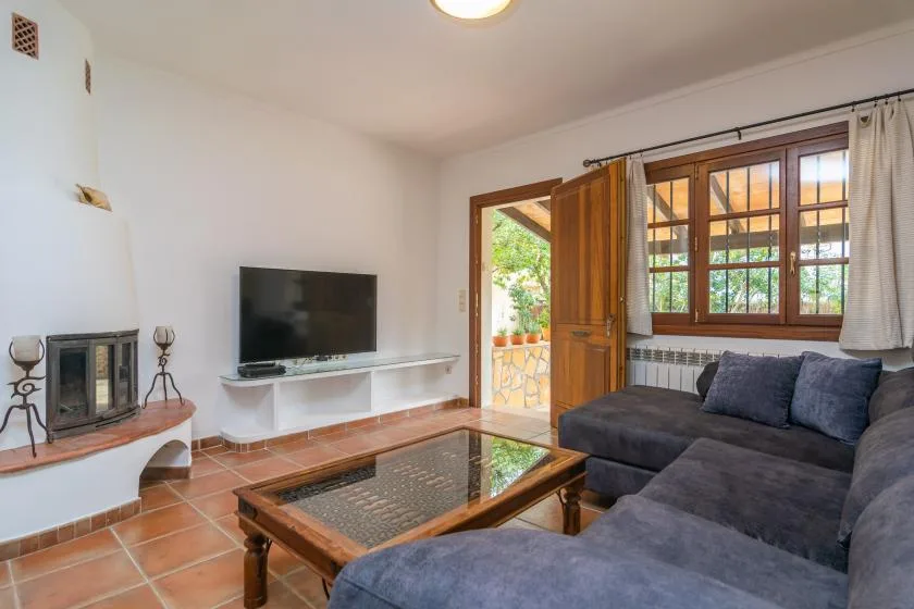 A living room with a television, coffee table, and seating beside an open doorway.
