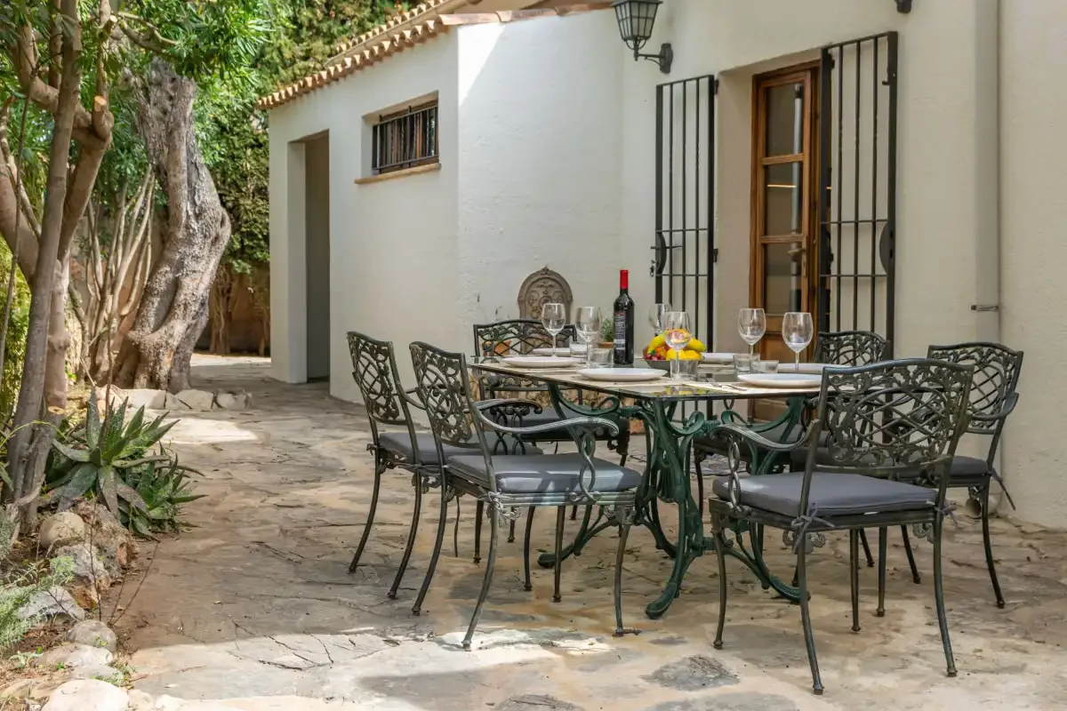 An outdoor dining area with a table and chairs beside a white building.