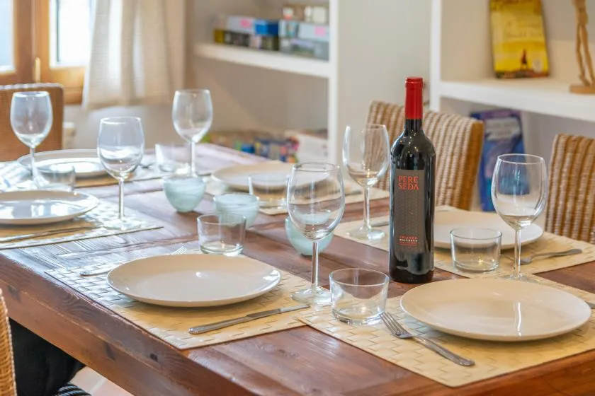A dining table is set with plates, glasses, and a bottle of wine.