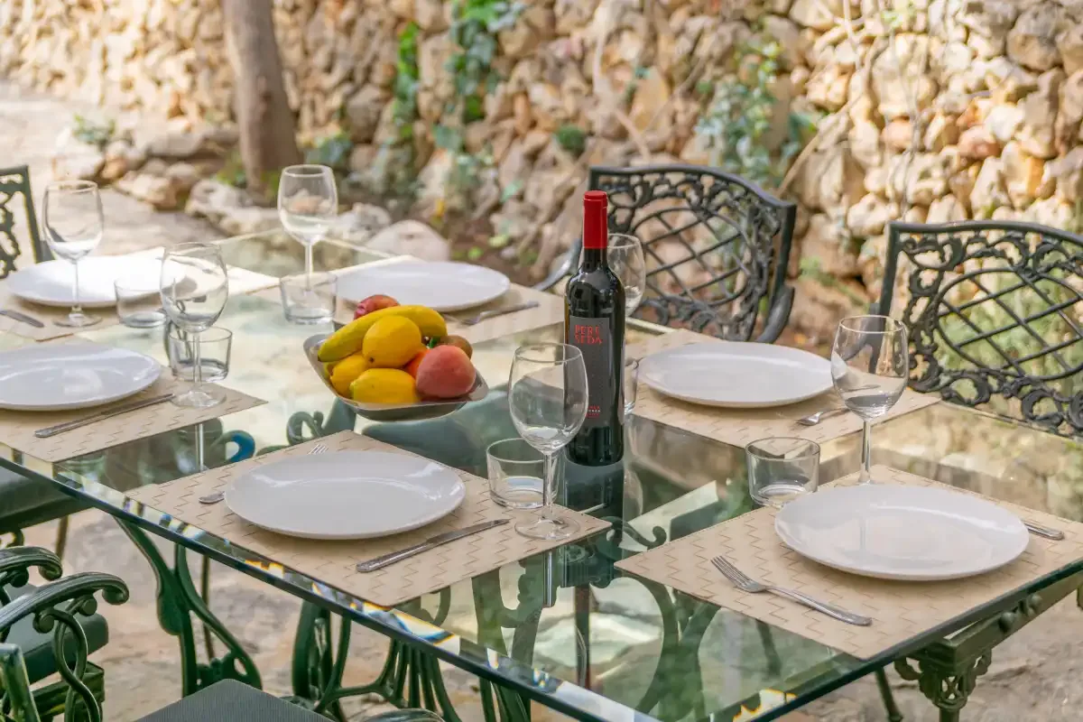 An outdoor dining area with a glass table set for a meal.