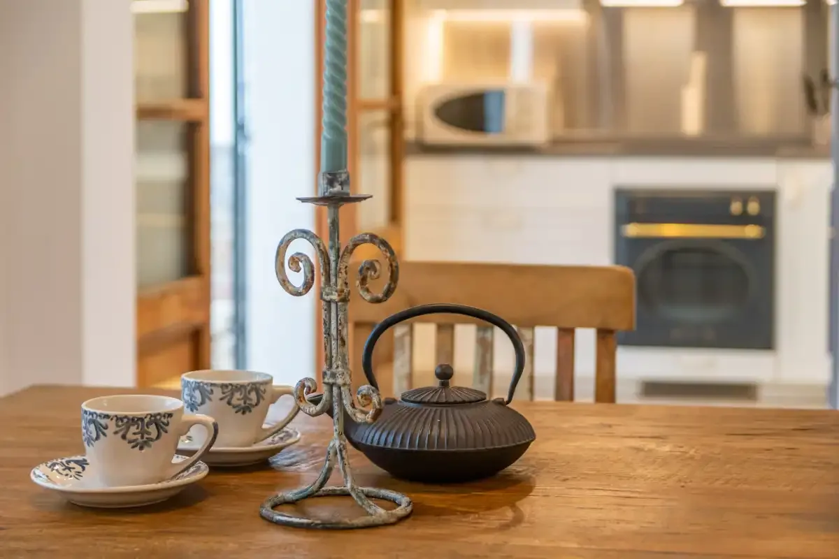 A dining table with teacups and a decorative candle holder in a kitchen.