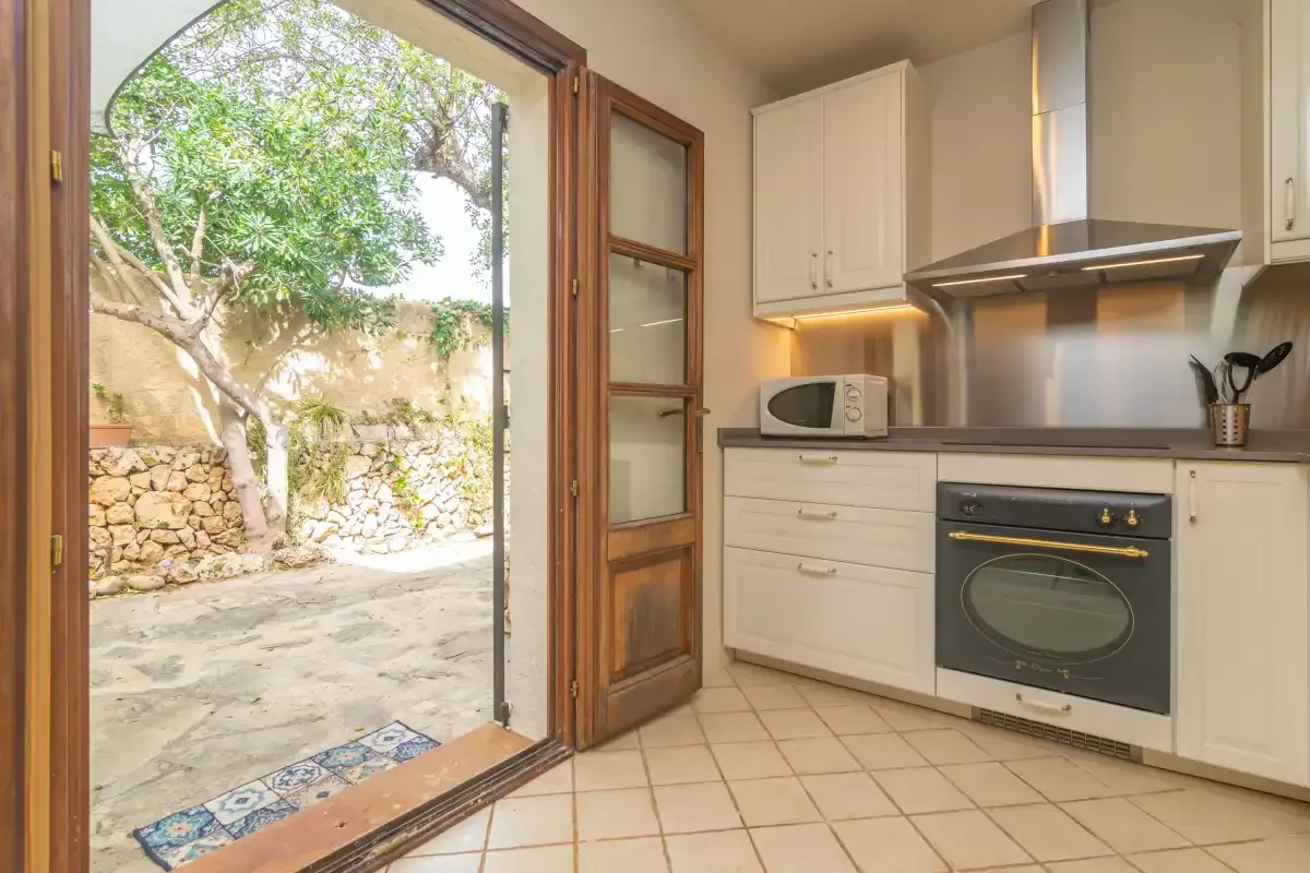 A kitchen opens onto a stone-paved patio through a wooden-framed doorway.