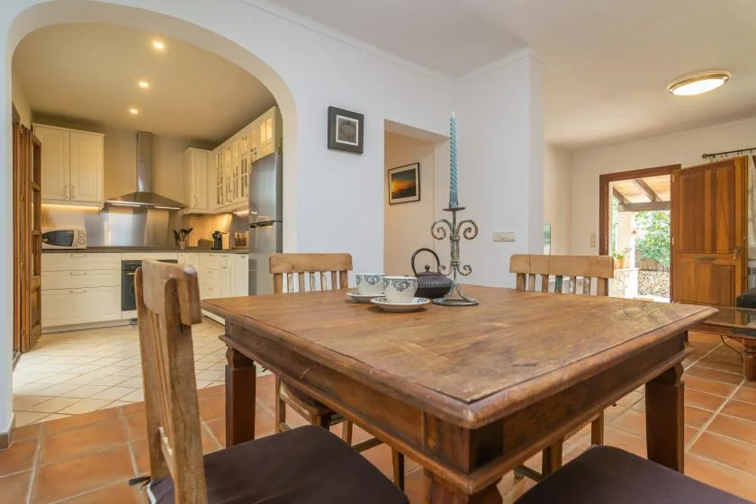 A dining area with a wooden table beside an open kitchen.
