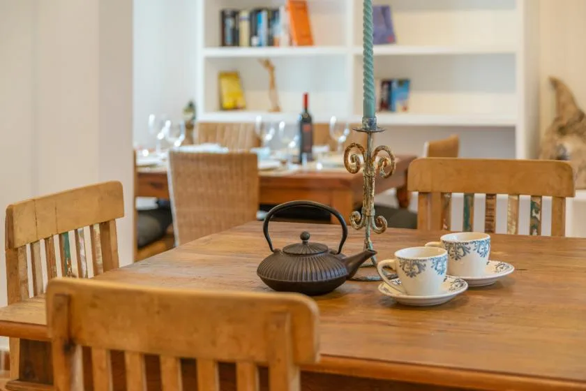 A dining area with a wooden table, teacups, and a teapot.