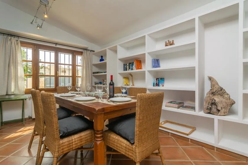A dining area with a wooden table and built-in white shelving.