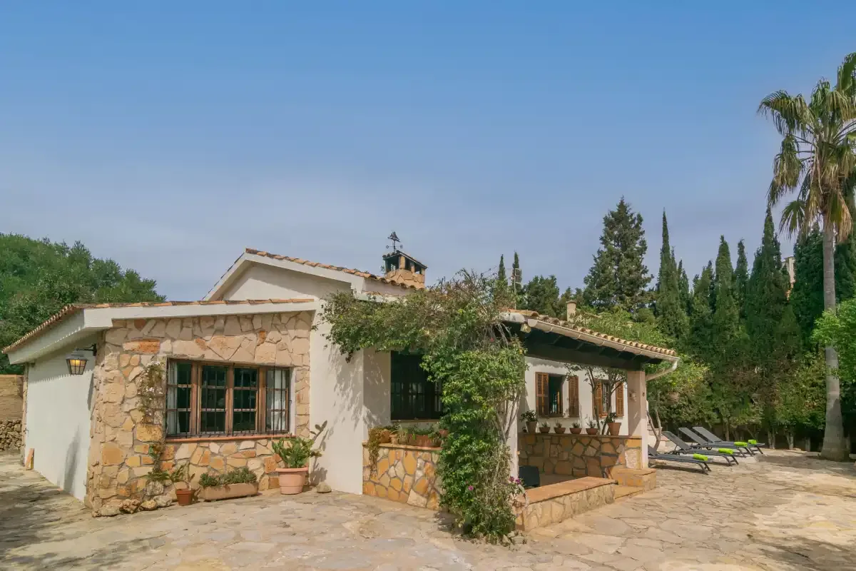 A stone-clad house with a paved patio and outdoor seating.